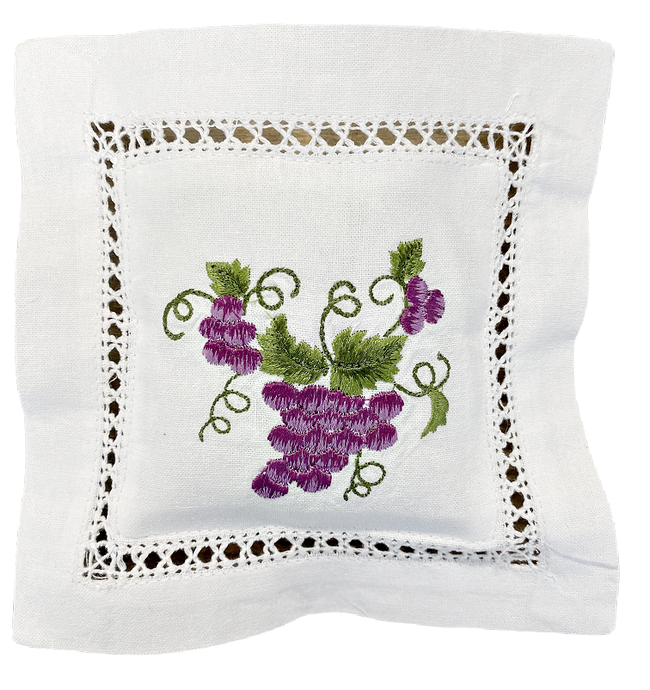 Laventelityyny brodeeratulla viinirypäletertun kuvalla jossa violetteja rypäleitä ja viininlehtiä, valkoinen puuvillatyyny jossa pitsireunaa La Petite Provence