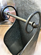 Harmaa metallinen vessapaperiteline mustalla kiehkuraisella pidikkeellä ja vararullasäiliöllä, lattialla seisova malli, yksityiskohta, La Petite Provence